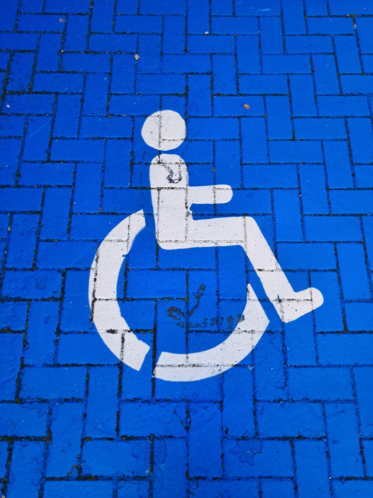White wheelchair symbol on a blue brick parking spot denoting accessibility.